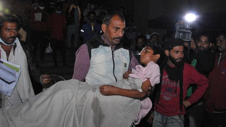 Ein Mann trägt ein Kind aus dem Kamla Nehru Children's Hospital im indischen Bhopal.