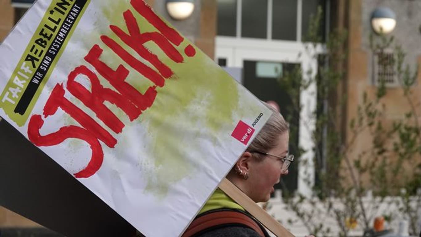 Eine Frau hält ein Schild hoch auf dem "Streik!" steht.