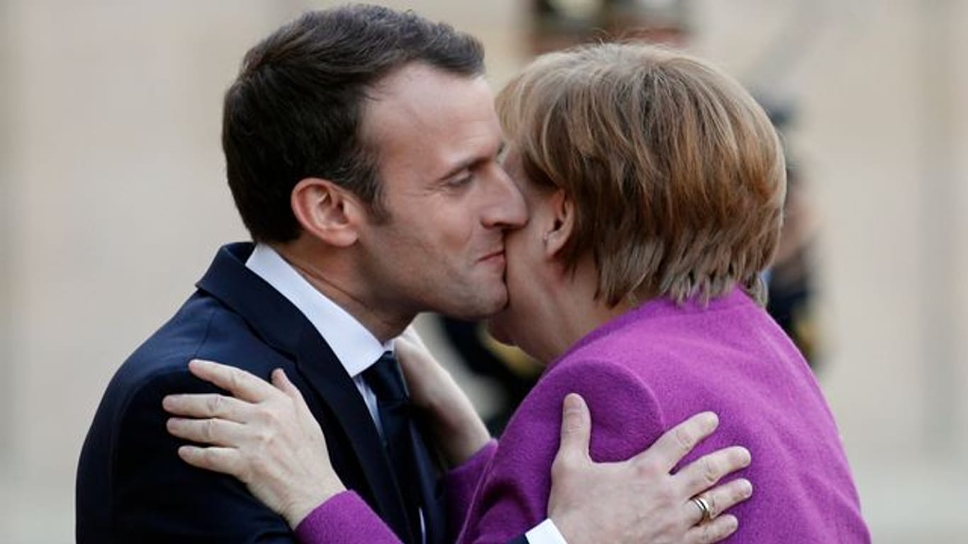 Frankreichs Präsident Emmanuel Macron und Noch-Bundeskanzlerin Angela Merkel geben sich Küsschen.