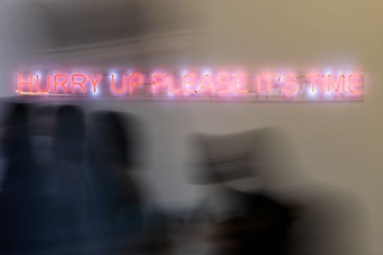 Konferenzteilnehmer gehen bei der UN-Klimakonferenz COP26 in Glasgow an einem Schriftzug der Künstlerin Cornelia Parker vorbei.