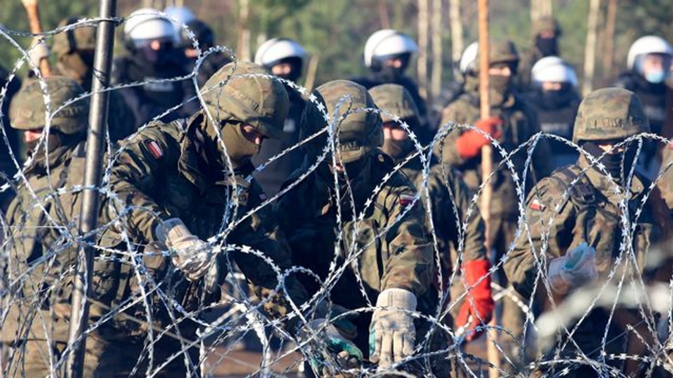 Polnische Polizisten und Grenzschützer stehen in Grodno am Stacheldrahtzaun.