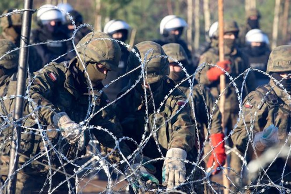 Polnische Polizisten und Grenzschützer stehen in Grodno am Stacheldrahtzaun.