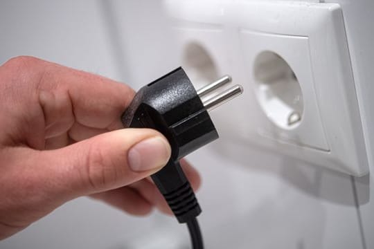Ein Stecker wird in eine Steckdose gesteckt.