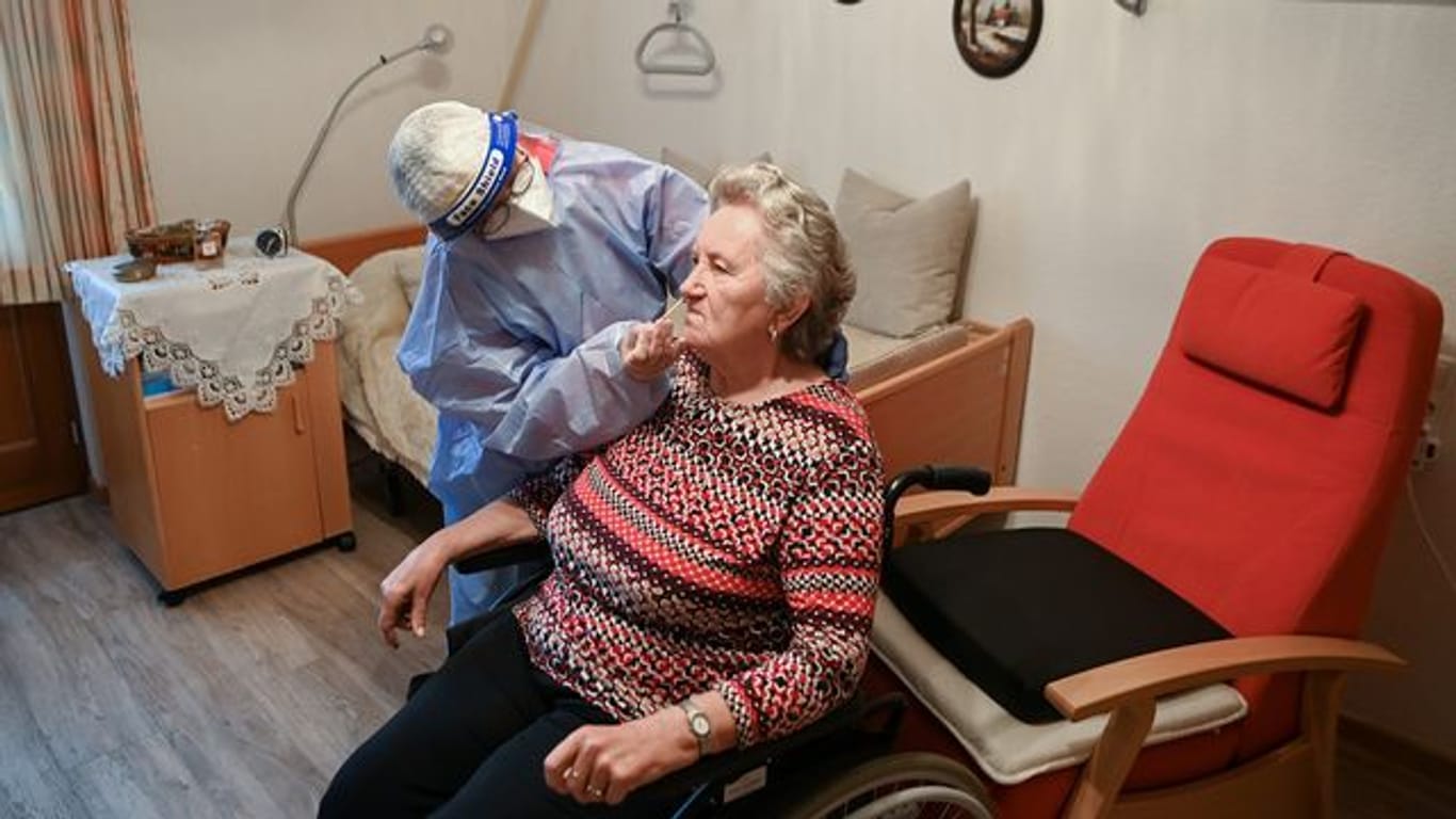 Die Krankenschwester eines mobilen Test-Teams des Deutschen Roten Kreuzes (DRK) testet in einer DRK-Seniorenbetreuungseinrichtung in Brandenburg eine Seniorin.