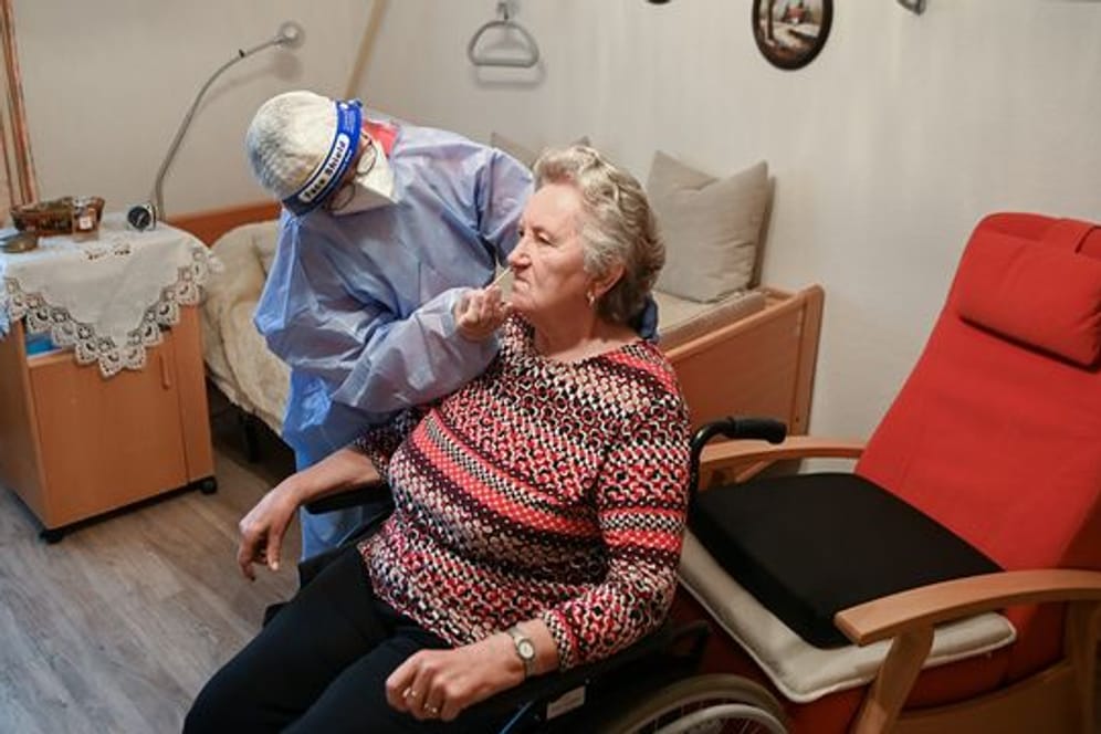 Die Krankenschwester eines mobilen Test-Teams des Deutschen Roten Kreuzes (DRK) testet in einer DRK-Seniorenbetreuungseinrichtung in Brandenburg eine Seniorin.