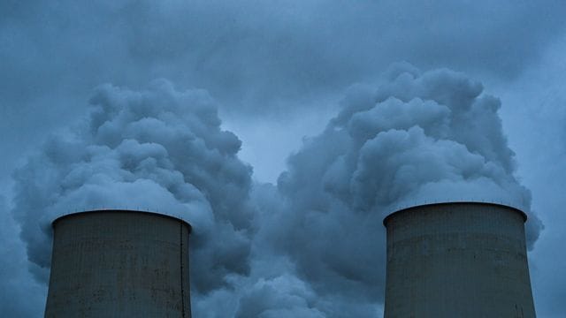 Wasserdampf steigt aus den Kühltürmen eines Braunkohlekraftwerks.