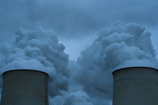 Wasserdampf steigt aus den Kühltürmen eines Braunkohlekraftwerks.