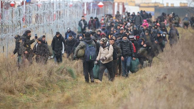 Migranten am Stacheldrahtzaun an der belarussisch-polnischen Grenze.