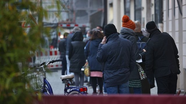 Menschen warten in einer langen Schlange vor einem Corona-Test- und Impfzentrum in Augsburg. Menschen warten in einer langen Schlange vor einem Corona-Test- und Impfzentrum in Augsburg.