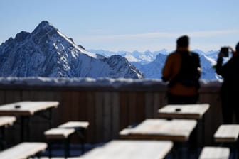 Zwei Besucher fotografieren von der Zugspitze aus das Panorama des Wettersteingebirges.