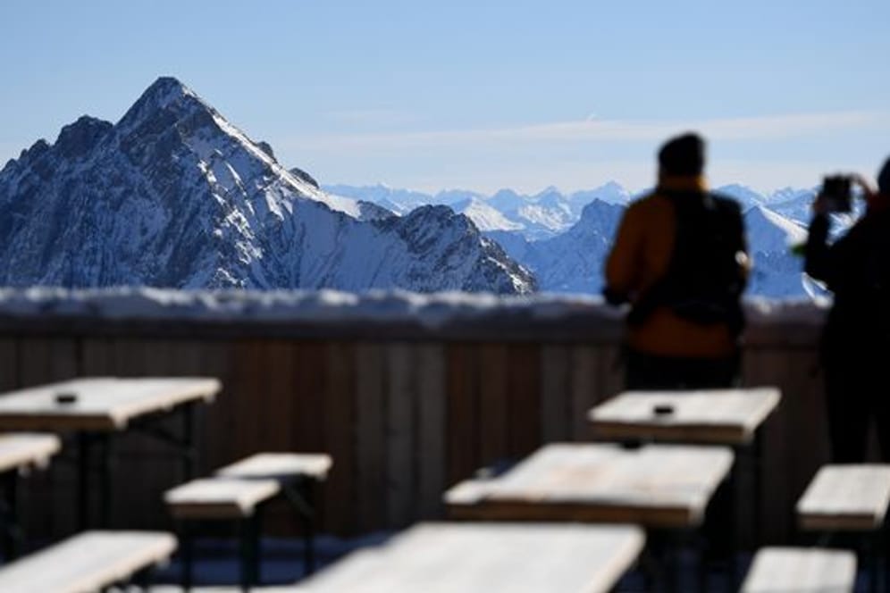 Zwei Besucher fotografieren von der Zugspitze aus das Panorama des Wettersteingebirges.