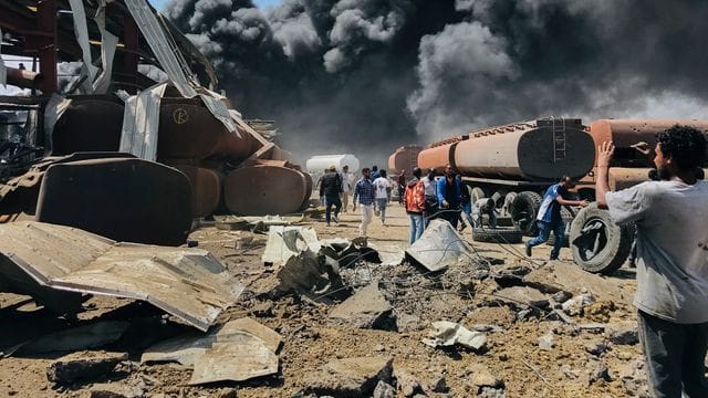 Menschen stehen nach einem Luftangriff auf die Hauptstadt der Region Tigray im Norden Äthiopiens vor schwarzen Rauchschwaden. Menschen stehen nach einem Luftangriff auf die Hauptstadt der Region Tigray im Norden Äthiopiens vor schwarzen Rauchschwaden.