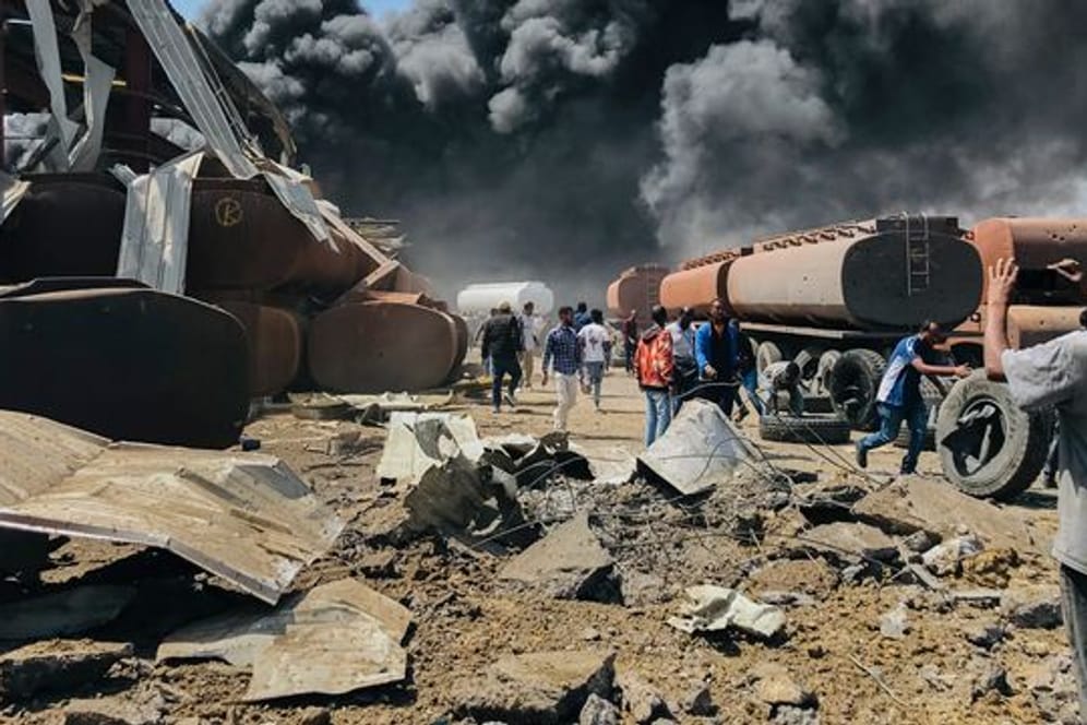 Menschen stehen nach einem Luftangriff auf die Hauptstadt der Region Tigray im Norden Äthiopiens vor schwarzen Rauchschwaden.