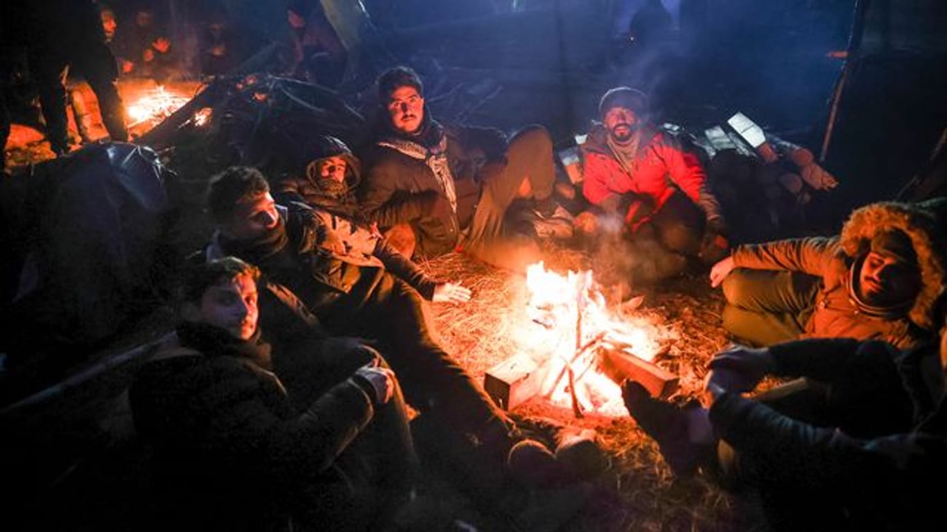 Migranten wärmen sich an einem Feuer an der belarussisch-polnischen Grenze auf.