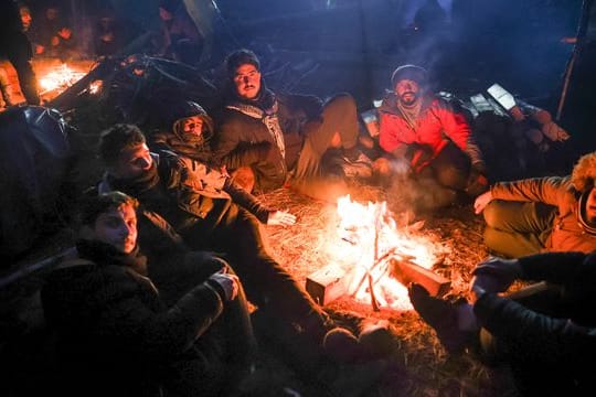 Migranten wärmen sich an einem Feuer an der belarussisch-polnischen Grenze auf.