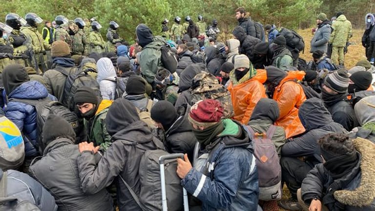 Migranten sitzen zusammen vor der Grenze in Belarus am gesperrten Übergang zu Polen: Der Irak will weitere 600 Geflüchtete ausfliegen.