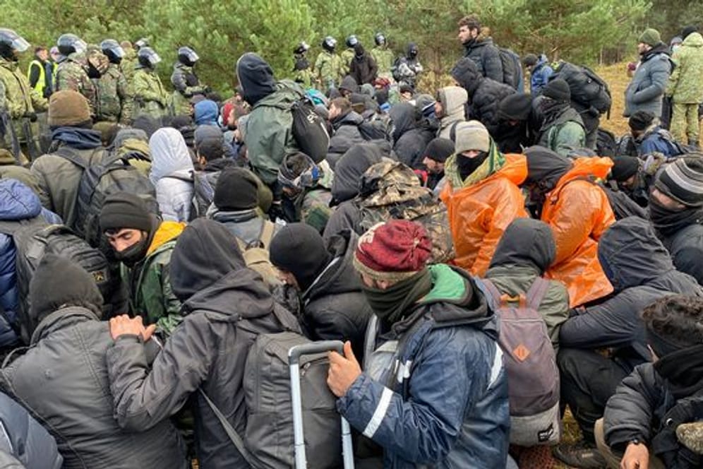 Migranten sitzen zusammen vor der Grenze in Belarus am gesperrten Übergang zu Polen: Der Irak will weitere 600 Geflüchtete ausfliegen.
