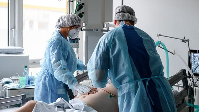 Die pflegerische Leitung der Intensivstation und Intensivstationsarzt bei einem Corona-Patienten auf der Intensivstation. Die pflegerische Leitung der Intensivstation und Intensivstationsarzt bei einem Corona-Patienten auf der Intensivstation.