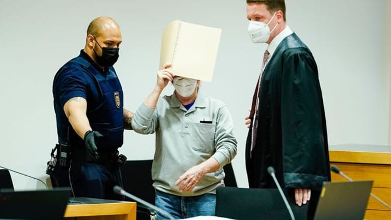Der Angeklagte (M) mit seinem Anwalt Steffen Lindberg (r) und einem Justizbeamten zu Prozessbeginn im September im Gericht.