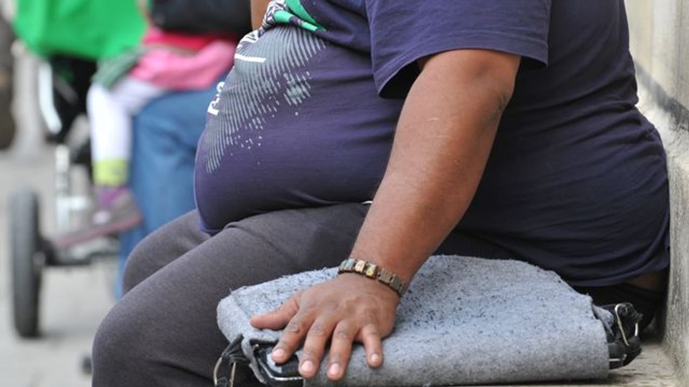 Ein Übergewichtiger sitzt auf einer Steinbank.