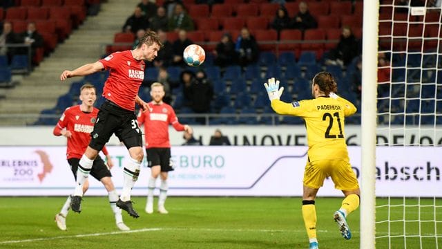 Hannovers Julian Börner (l) verpasst mit einem Kopfball nur knapp das Tor von Paderborns Torwart Jannik Huth.