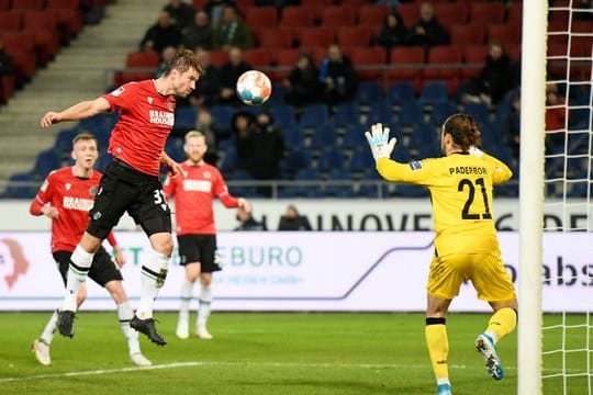 Hannovers Julian Börner (l) verpasst mit einem Kopfball nur knapp das Tor von Paderborns Torwart Jannik Huth.