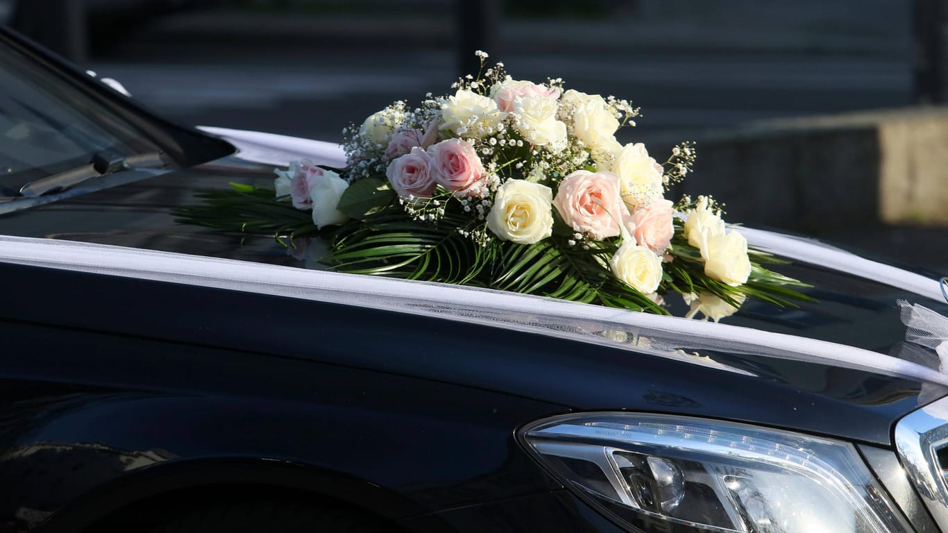 Ein Hochzeitsstrauß liegt auf der Motorhaube eines Autos (Symbolbild): In Köln hat ein Hochzeitskorso ein schlechtes Ende genommen.