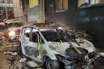 Ausgebrannte Autos, darunter auch Polizeifahrzeuge, stehen auf einer Straße in Rotterdam.