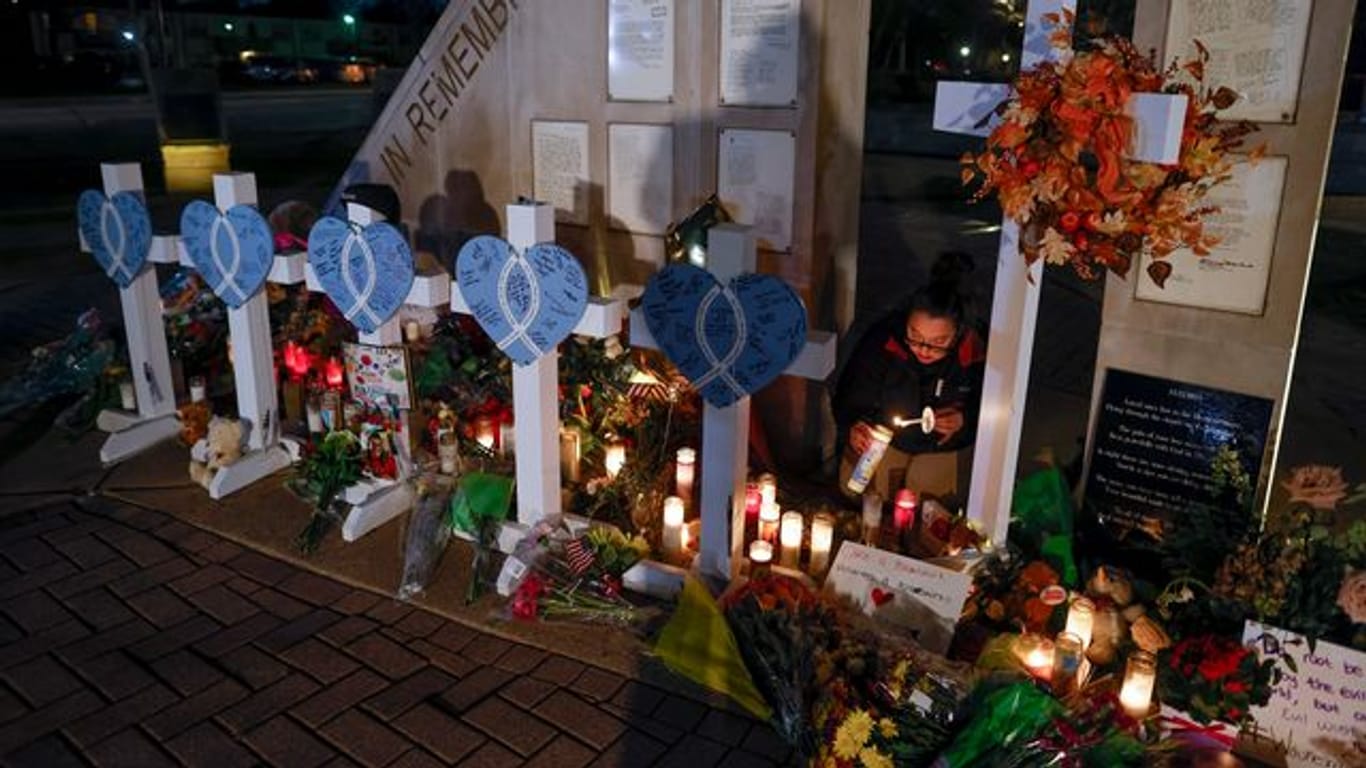 Eine Frau zündet Kerzen an einer Gedenkstätte im Veteran's Park für die Opfer an, nachdem ein Geländewagen am Sonntag in eine Weihnachtsparade gerast war, bei der mehrere Menschen getötet und Dutzende verletzt wurden.