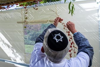 Mitglieder der jüdischen Gemeinde in Schwerin schmücken die traditionelle Laubhütte mit Zweigen und Früchten.