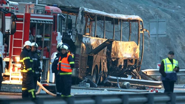Rettungskräfte der Feuerwehr an der Unfallstelle neben dem ausgebrannten Bus. Rettungskräfte der Feuerwehr an der Unfallstelle neben dem ausgebrannten Bus.