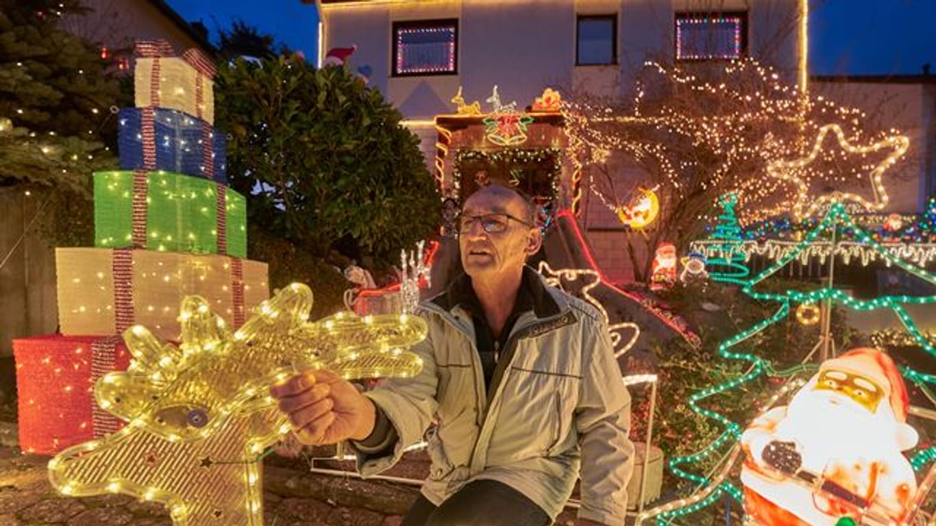 Rentner Josef Johann baut vor seinem Haus im Moseldorf Klotten bunte leuchtende Weihnachtsdekoration auf.