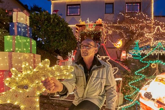 Rentner Josef Johann baut vor seinem Haus im Moseldorf Klotten bunte leuchtende Weihnachtsdekoration auf.