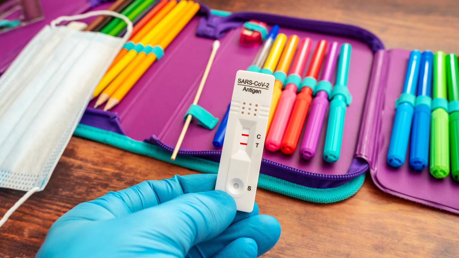 Ein Corona-Schnelltest wird vor ein Federmäppchen gehalten (Symbolbild): Auch an den Schulen sorgen die Maßnahmen für zusätzliche Belastung. Ein Corona-Schnelltest wird vor ein Federmäppchen gehalten (Symbolbild): Auch an den Schulen sorgen die Maßnahmen für zusätzliche Belastung.