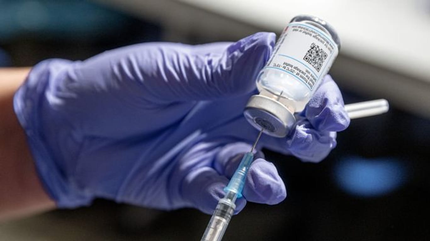 Eine Krankenschwester zieht Corona-Impfstoff aus einer Ampulle in eine Spritze auf.