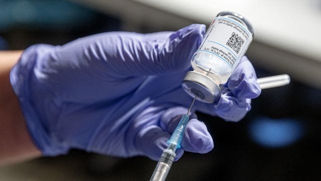 Eine Krankenschwester zieht Corona-Impfstoff aus einer Ampulle in eine Spritze auf. Eine Krankenschwester zieht Corona-Impfstoff aus einer Ampulle in eine Spritze auf.