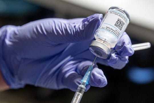 Eine Krankenschwester zieht Corona-Impfstoff aus einer Ampulle in eine Spritze auf.