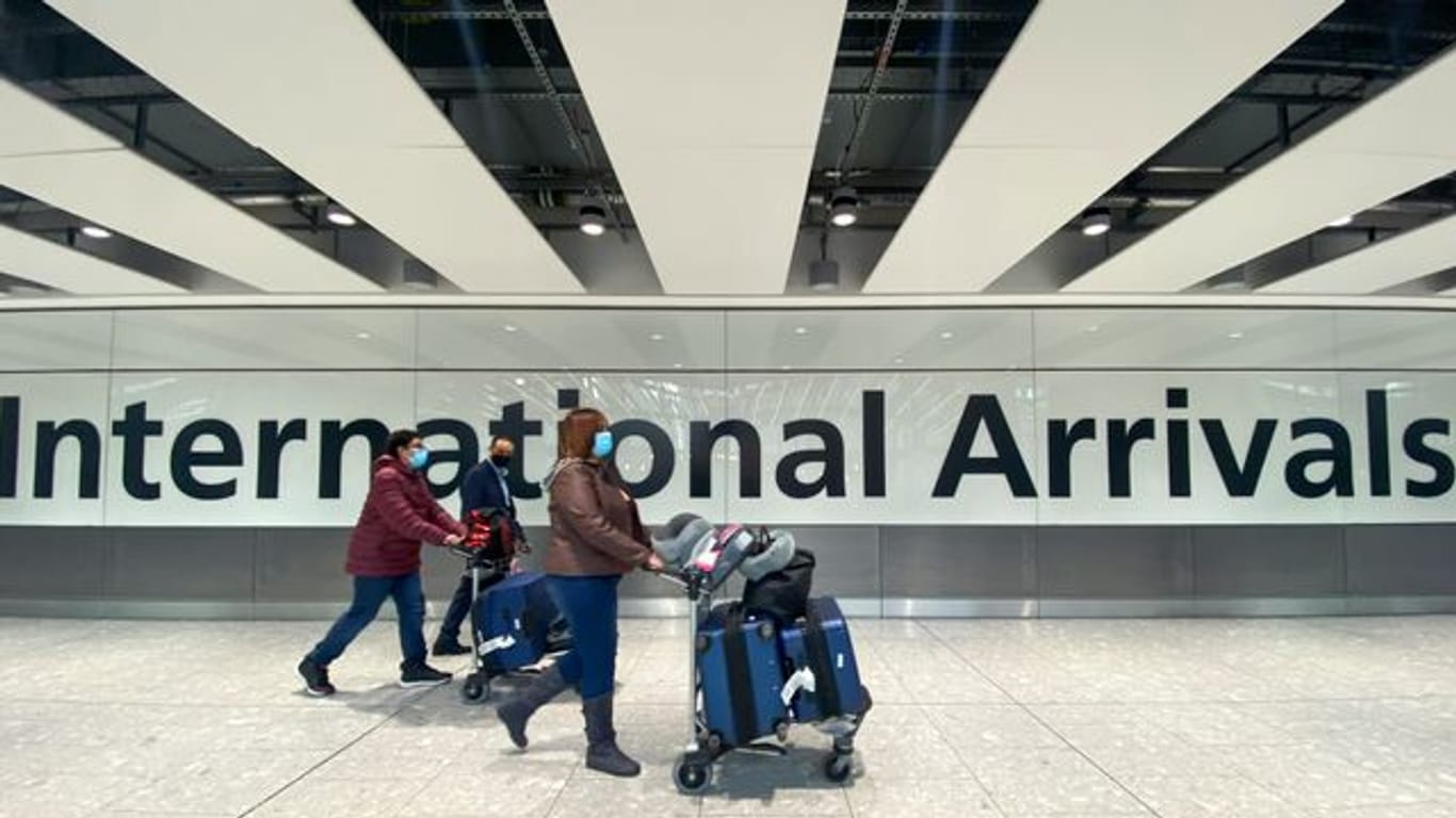 Passagiere gehen mit ihrem Gepäck durch das Ankunftsterminal eines Flughafens.