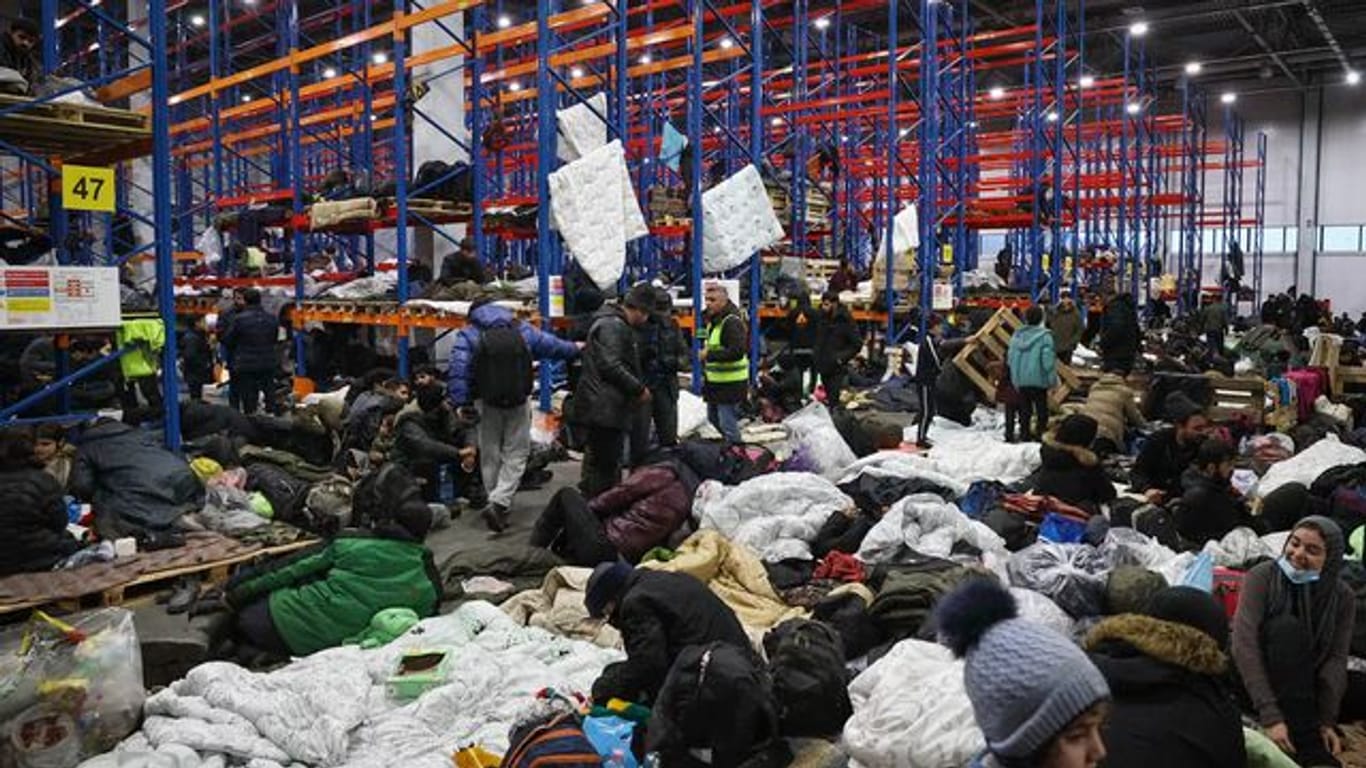 Migranten, die sich für die Nacht im Logistikzentrum am Kontrollpunkt "Kuznica" an der belarussisch-polnischen Grenze einrichten.