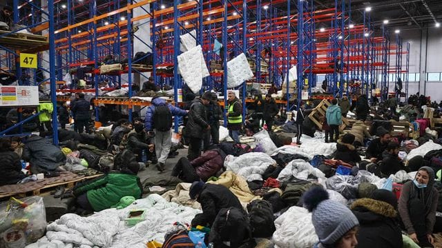 Migranten, die sich für die Nacht im Logistikzentrum am Kontrollpunkt "Kuznica" an der belarussisch-polnischen Grenze einrichten.