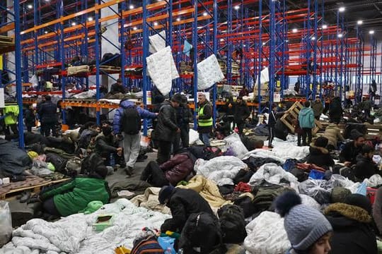 Migranten, die sich für die Nacht im Logistikzentrum am Kontrollpunkt "Kuznica" an der belarussisch-polnischen Grenze einrichten.