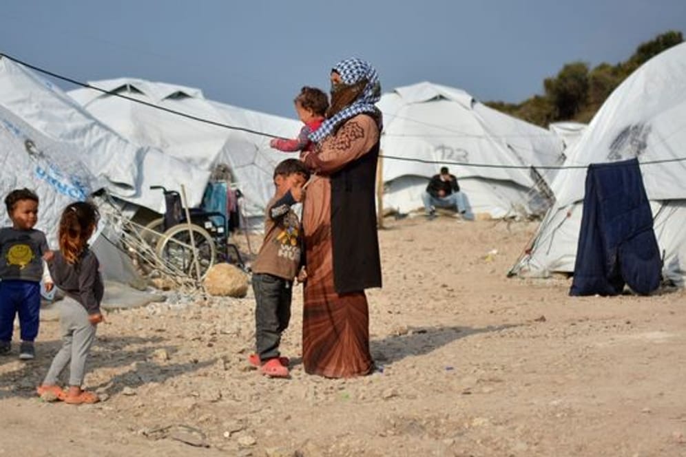 Eine Frau steht mit einem Baby im Arm und drei kleinen Kindern im Flüchtlingslager Kara Tepe in der Nähe von Mytilini auf Lesbos zwischen Zelten.