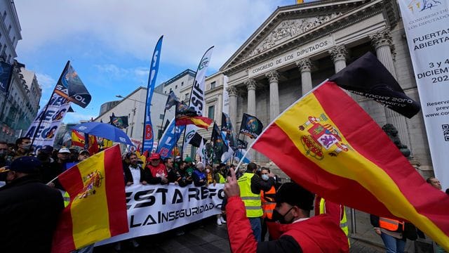 Polizisten laufen während des Protestmarsches am spanischen Parlament in Madrid vorbei.