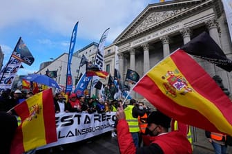 Polizisten laufen während des Protestmarsches am spanischen Parlament in Madrid vorbei.