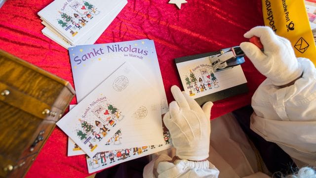 Der Nikolaus stempelt in der Nikolaushütte einen Brief ab.