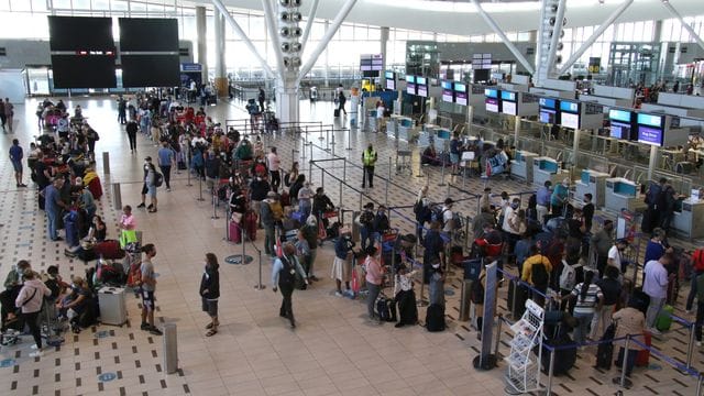 Reisende stehen am Flughafen in Kapstadt in langen Schlangen an den wenigen Schaltern an, die überhaupt noch offen sind. Reisende stehen am Flughafen in Kapstadt in langen Schlangen an den wenigen Schaltern an, die überhaupt noch offen sind.