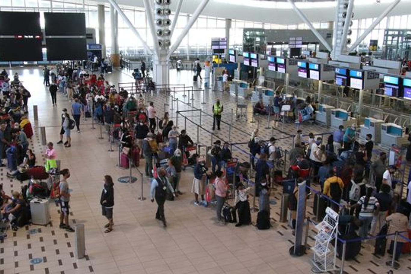 Reisende stehen am Flughafen in Kapstadt in langen Schlangen an den wenigen Schaltern an, die überhaupt noch offen sind.