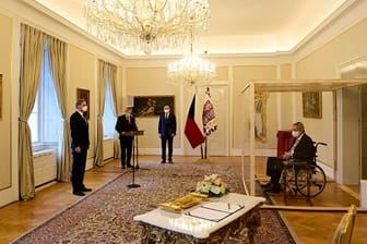 Der tschechische Präsident Milos Zeman (r) sitzt während der Vereidigung von Petr Fiala (l) in einem Rollstuhl hinter einer durchsichtigen Wand.