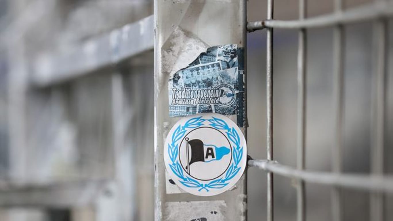 Ein Aufkleber mit dem Logo von Arminia Bielefeld klebt auf einem Zaun.