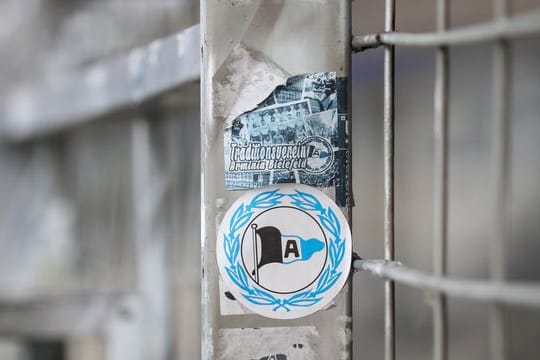 Ein Aufkleber mit dem Logo von Arminia Bielefeld klebt auf einem Zaun.